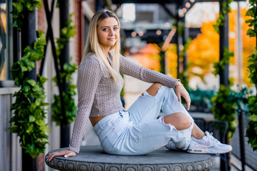 Senior girl sits on a table outside Top of the Market in downtown Dayton during her senior pictures with Studio 22 Photography.