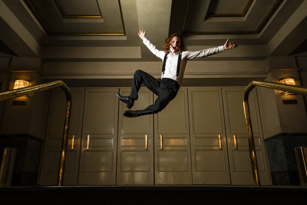 Muse Machine senior guy jumps in the air and heel clicks at the entrance of Victoria Theatre in downtown Dayton.