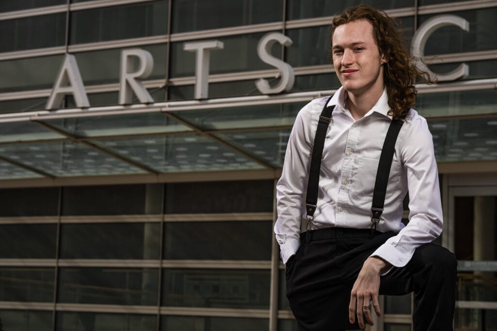 Senior guy from Carroll High School poses in front of the Schuster Center in downtown Dayton during his senior pictures with Studio 22 Photography.