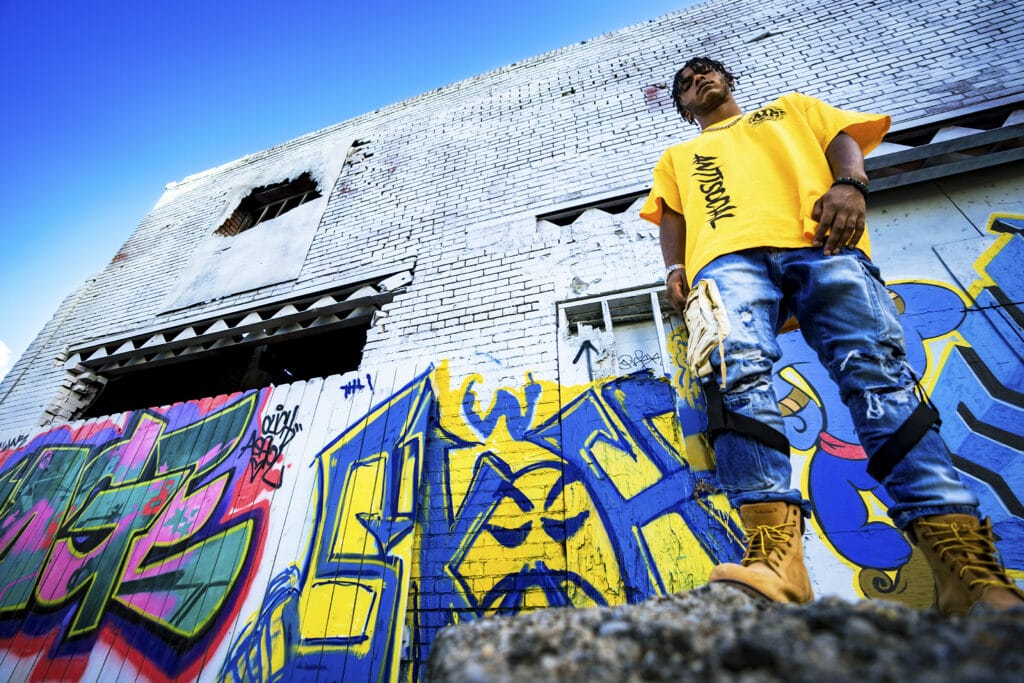 Senior guy stands on a rock in front of graffiti during senior photo session in Dayton, Ohio.