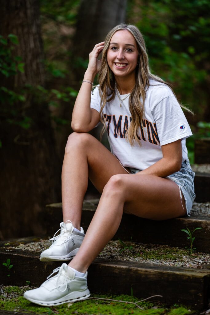 Taylor Scohy, a senior at Bellbrook High School, sits on rustic outdoor steps wearing jean shorts and a white UT Martin t-shirt